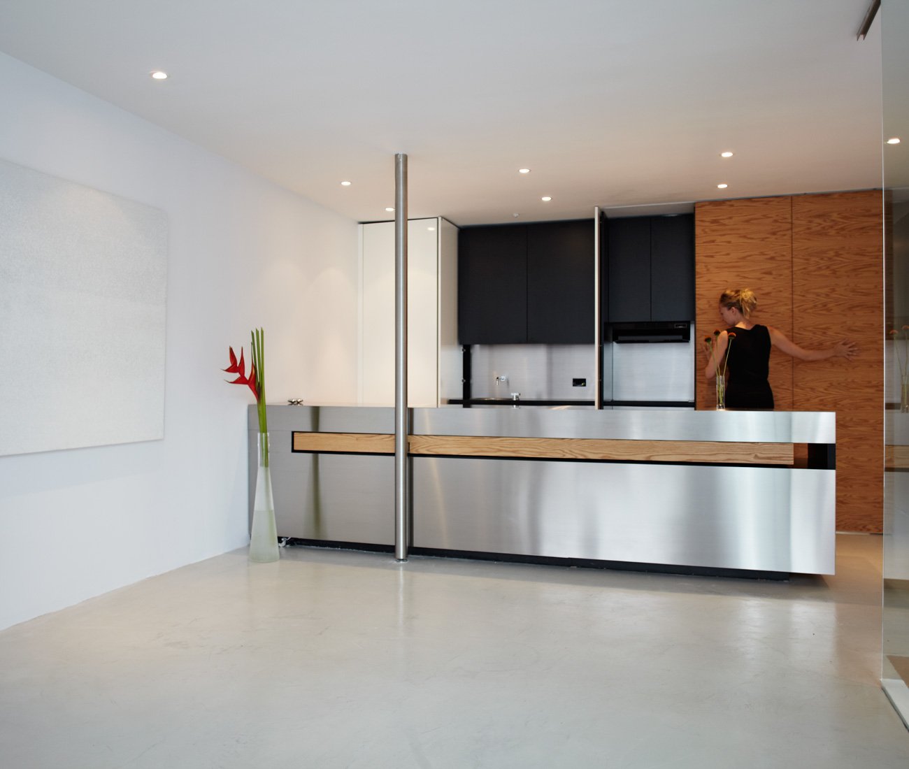 transforming home - White polyurethane-finished MDF cabinets conceal a fridge, sink and storage, and the sliding wood door hides the stove.
