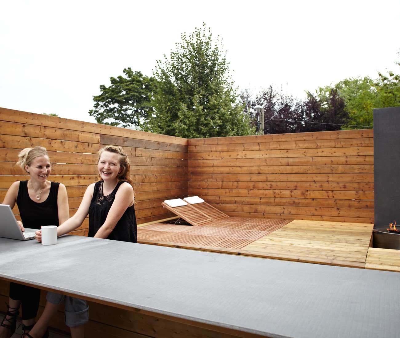 Rooftop patio features a bar clad in white acrylic and stainless steel