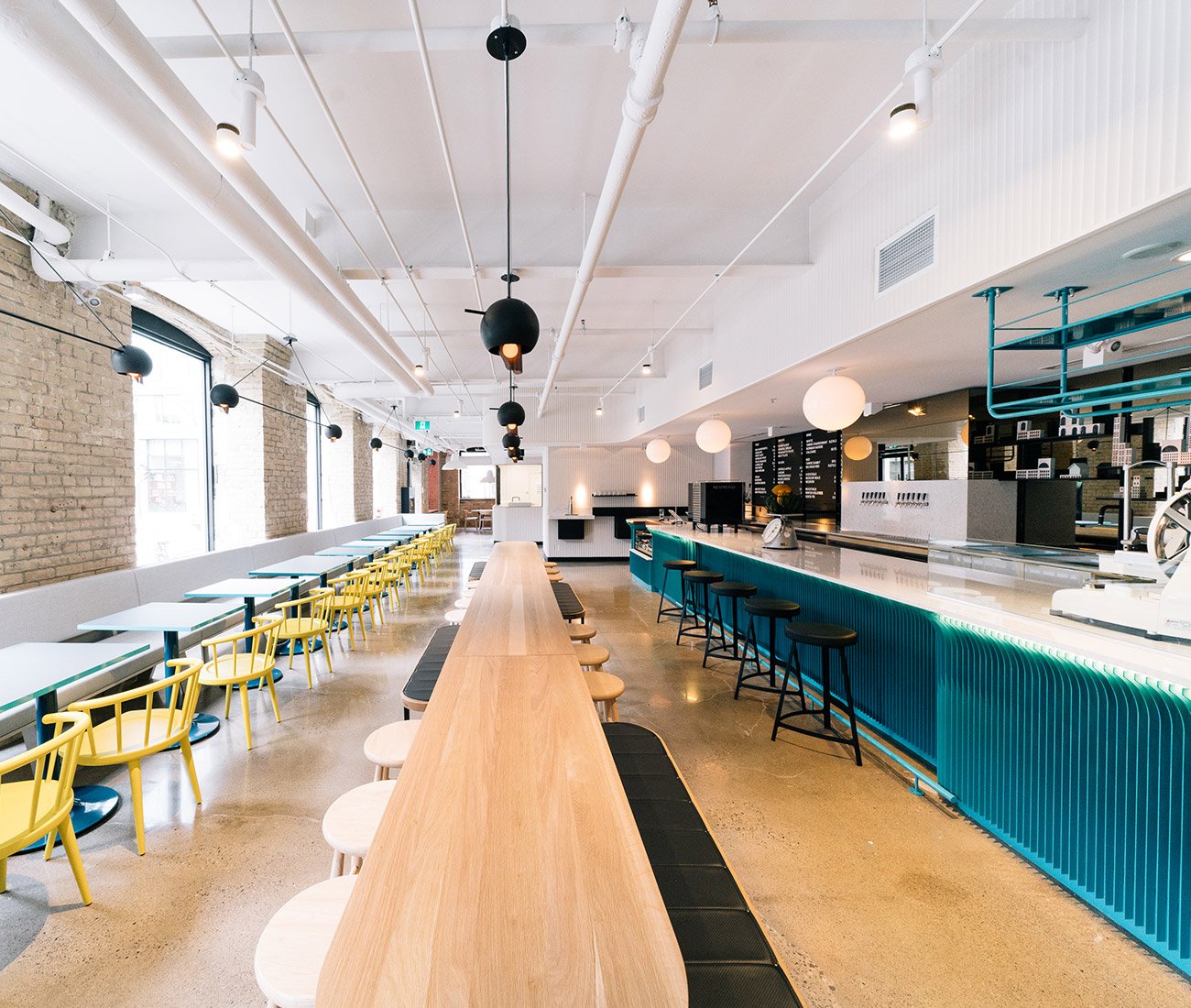 Interior view of General Assembly showcasing the communal table and stylish decor. Pizza Toronto Design Restaurant