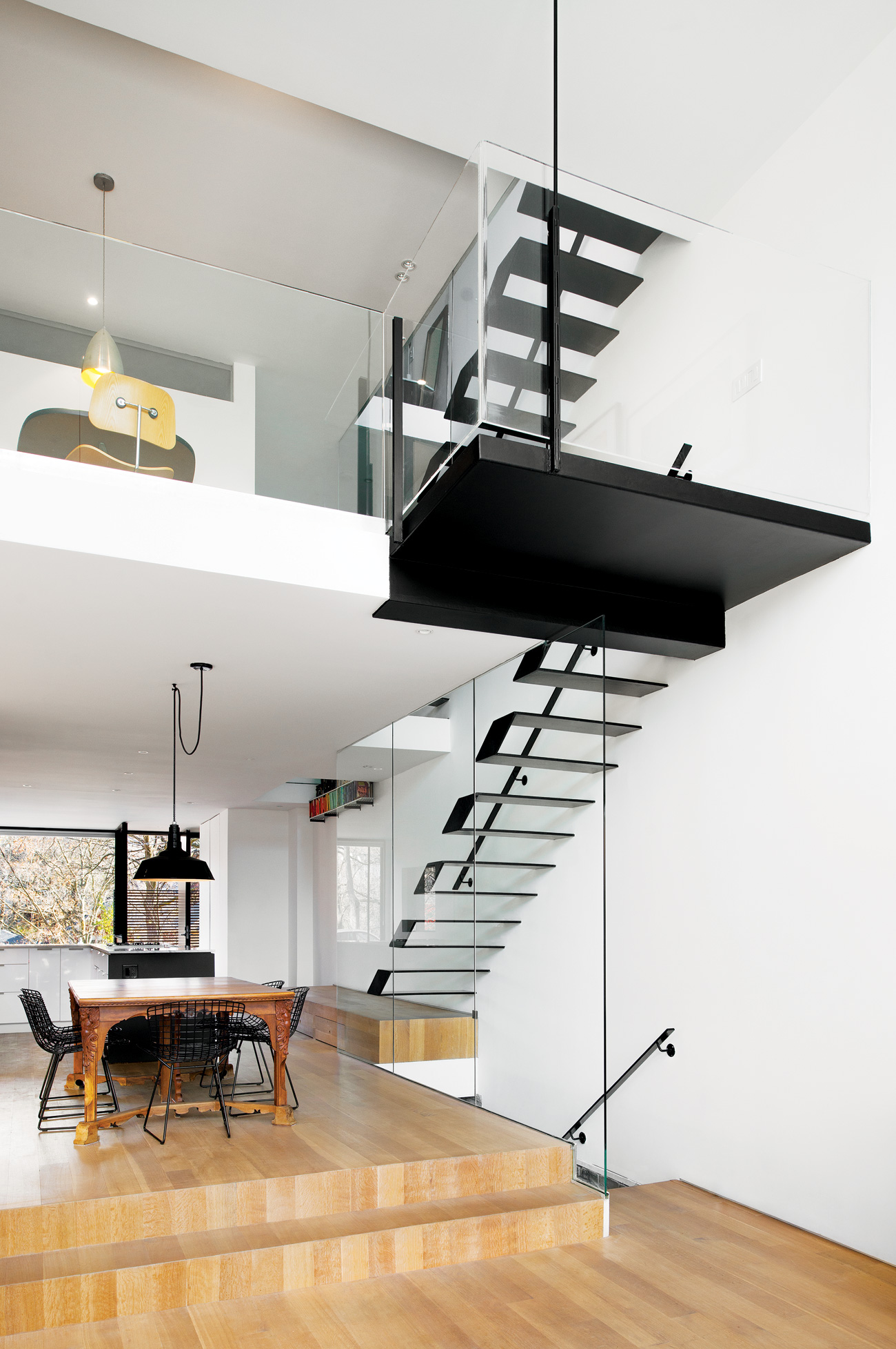 Double-height living room to the dining area and second floor landing, featuring angled white oak flooring of the modern east end home by Designer Johnson Chou