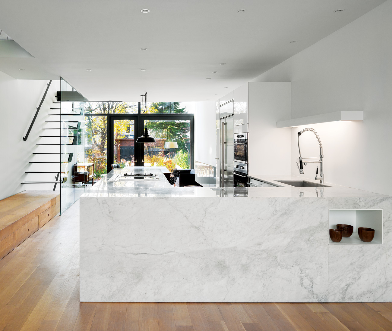 Modern kitchen with a custom island featuring carved nooks and a marble countertop - designer Johnson Chou