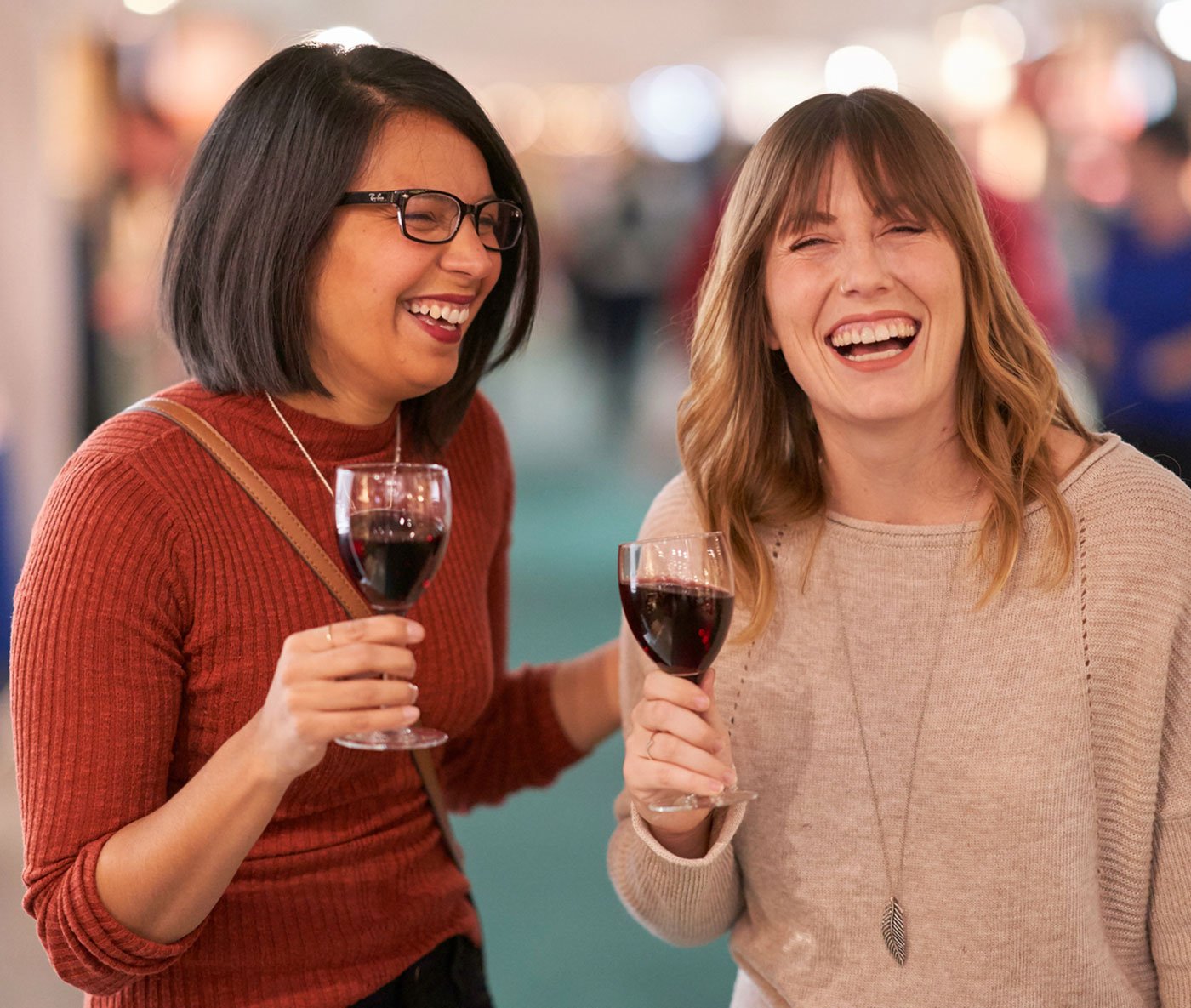 A couple of young women with a glass of wine are laughing at the One of a Kind Winter Show 2018