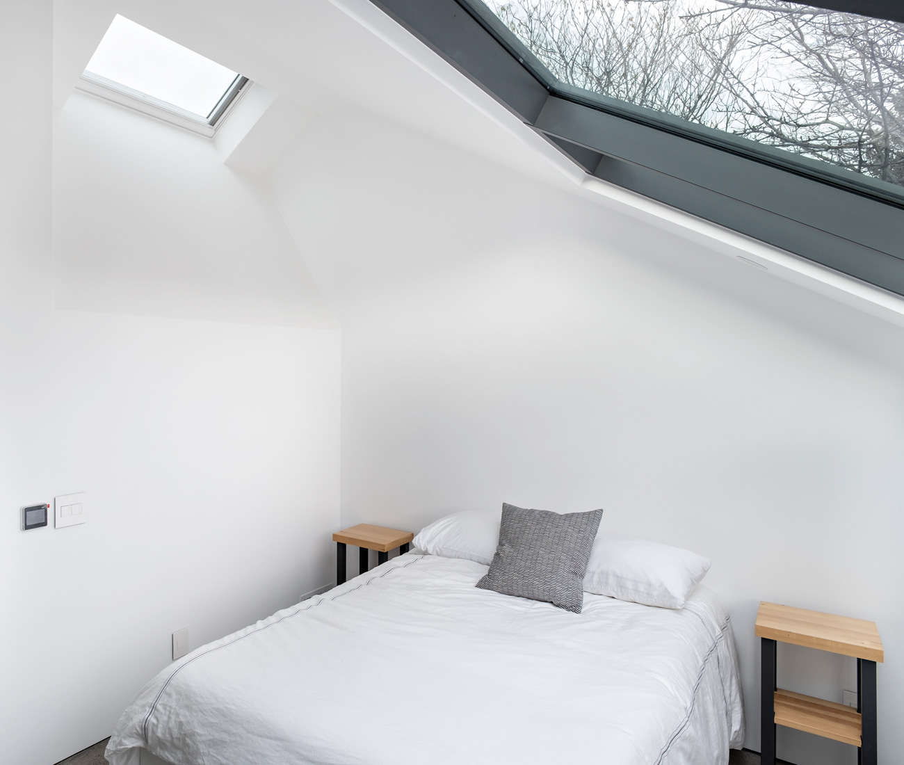LGA Architects Laneway House Harbord Village Designlines Magazine Guest bedroom with mitred glass window offering full neighborhood views; Ikea bed.
