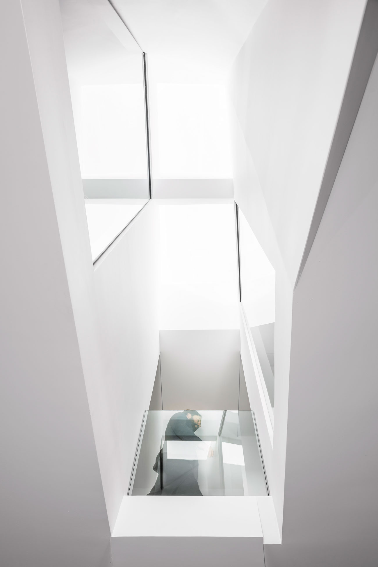 Phaedrus Studio Tesseract House Designlines Magazine Long Branch Home Staircase landing with views up to a Velux skylight, down to the first floor, and across to two staggered interior windows.