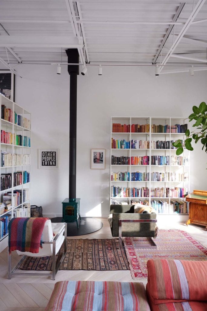 Living room design with libraries and books along the wall, chairs around a central room fireplace