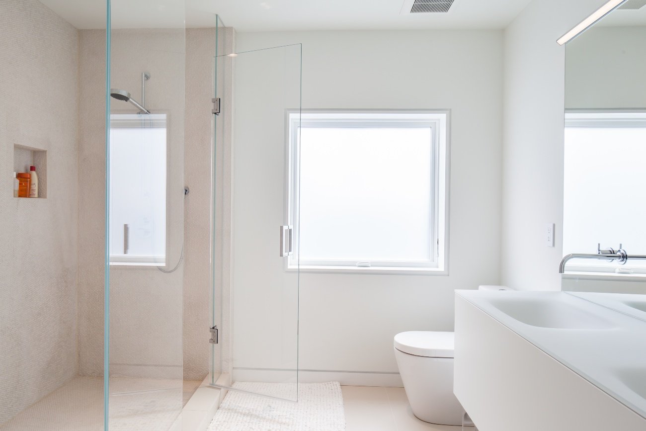 Shared bathroom in an attic between kids' rooms, featuring minimal design, a spacious shower, and a floating vanity with two sinks.