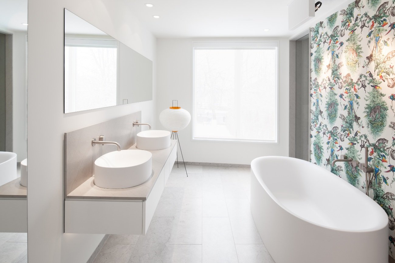 Modern Bathroom renovations - White bathroom with pebble floors, a floating vanity, and a soaker tub with jungle wallpaper.