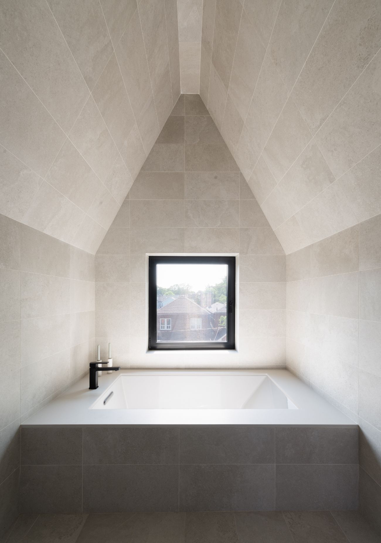 Open-concept modern bathroom renovation with a doorless bathing area and a spa-like tub zone in warm grey ceramic.