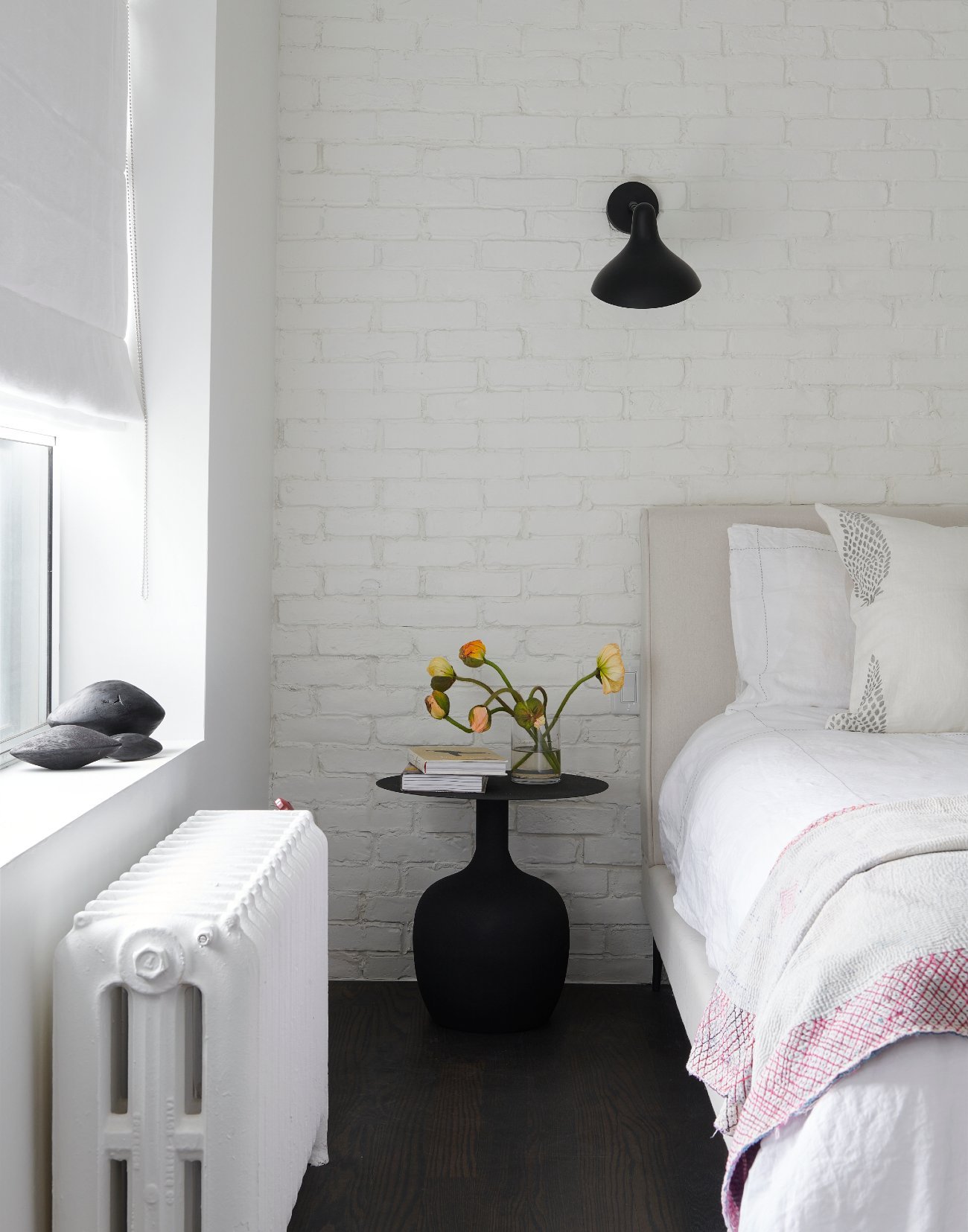 Side table near bed with flowers in a vase