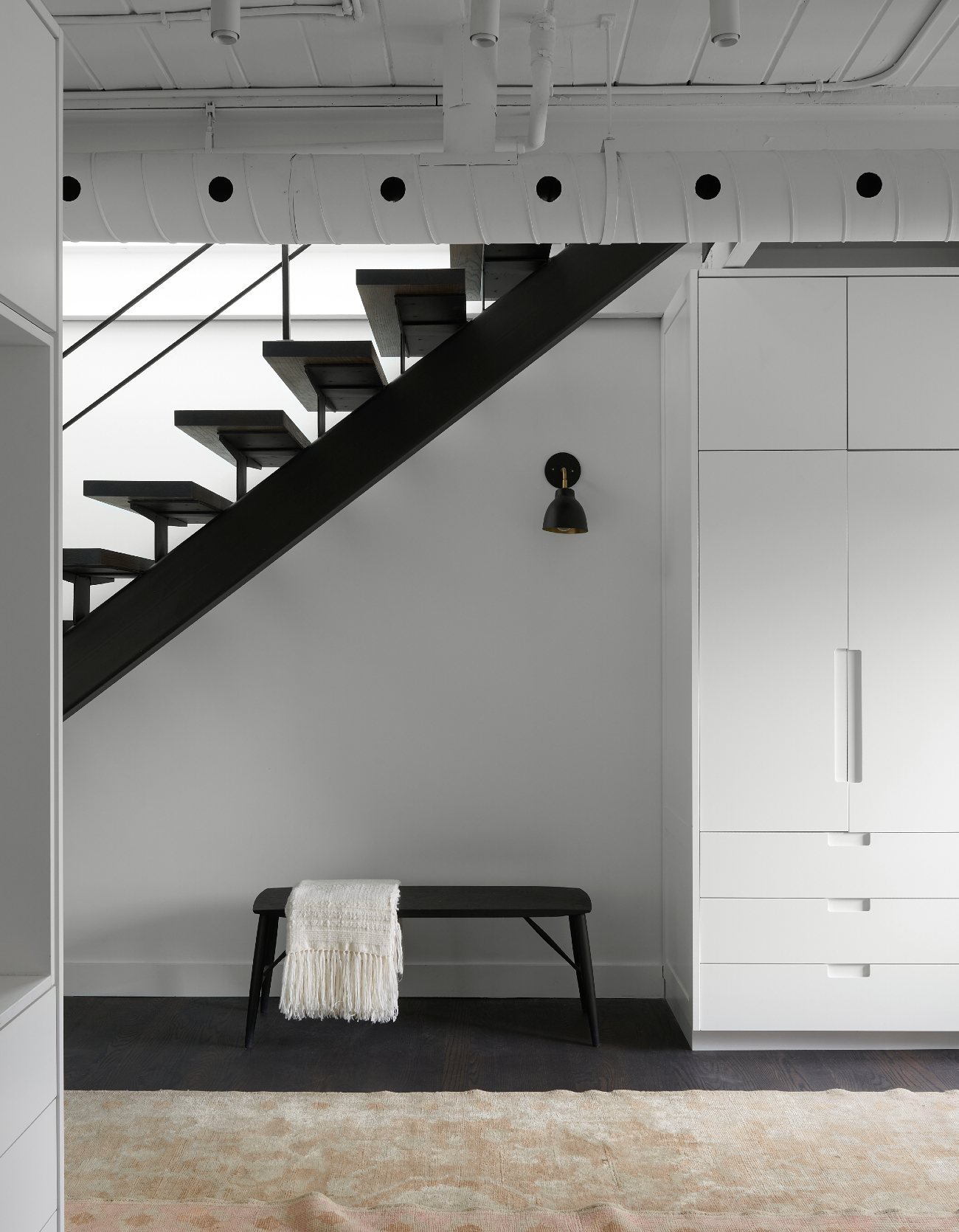 Bench under stairs in a renovated warehouse loft by Suzanne Dimma