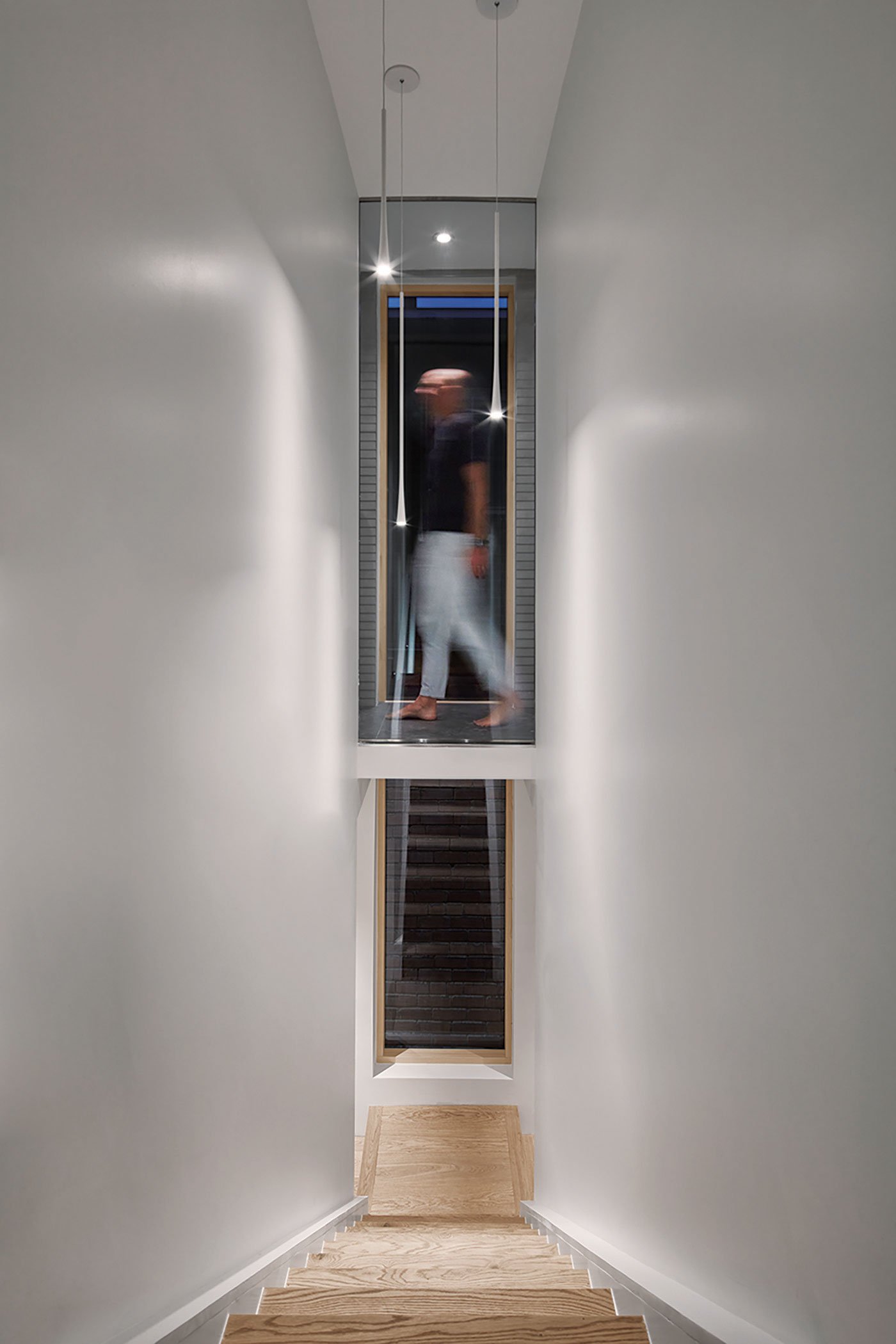 A glass-encased bridge links the principal bedroom with the bathroom while preserving the stairway’s view to the back of the house - Reflect Architecture | Wychwood House